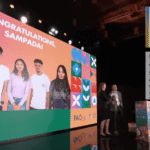 A group of five young people from Nepal's Team Sampada are shown virtually on a large screen with the words "CONGRATULATIONS, SAMPADA!". In the foreground, two award certificates are visible: one for the "Youth Food Lab Award (EUR 1000)" and one for the "Youth Food Lab x Learning Factory Award," both recognizing SAMPADA.