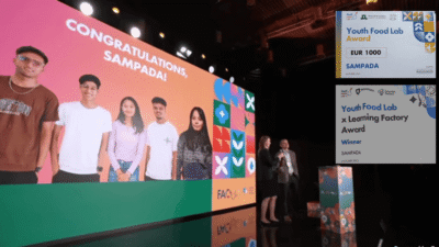 A group of five young people from Nepal's Team Sampada are shown virtually on a large screen with the words "CONGRATULATIONS, SAMPADA!". In the foreground, two award certificates are visible: one for the "Youth Food Lab Award (EUR 1000)" and one for the "Youth Food Lab x Learning Factory Award," both recognizing SAMPADA.